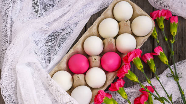 istock Happy Easter. White and pink chicken eggs, in a stand on a wooden background with red carnation flowers. Concept of holidays. 1301840096
