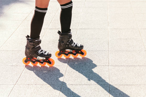 Close-up of a woman's legs skating with inline skates outdoors on a hot and very sunny summer day. The shadow is projected on the stone floor. Copy space stock photo