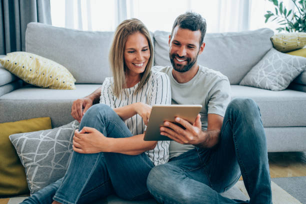 istock Smiling young couple using digital tablet at home. 1301844606
