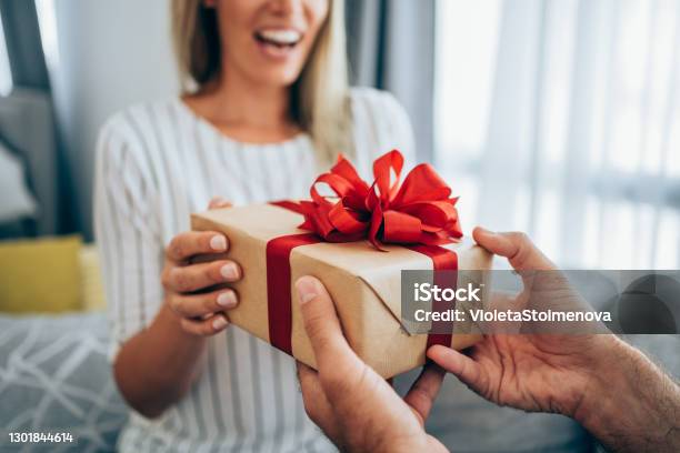 Cheerful Young Woman Receiving A Gift From Her Boyfriend Stock Photo - Download Image Now