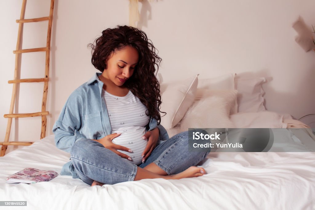young pretty african american woman pregnant laying in bed, lifestyle people concept young pretty african american woman pregnant laying in bed, lifestyle people concept close up Pregnant Stock Photo