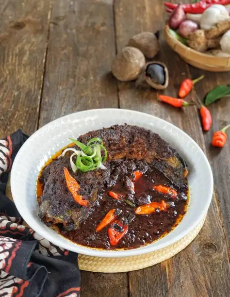 Indonesian Betawi specialties, Gabus Pucung. Namely, fried snakehead fish in black sauce seasoned with keluak nuts, garlic, shallots, turmeric, red chilies, candlenut and bird eyes chilies.