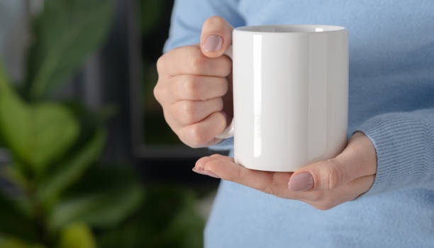 istock Female hands hold mock up white empty mug, cup for your design and logo closeup. Template blank for promotional text message or promotional content. 1301850105