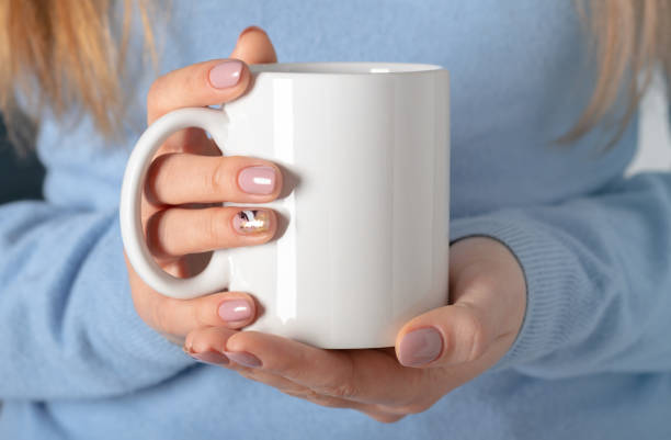 istock Female hands hold mock up white empty mug, cup for your design and logo closeup. Template blank for promotional text message or promotional content. 1301850108