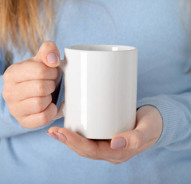 istock Female hands hold mock up white empty mug, cup for your design and logo closeup. Template blank for promotional text message or promotional content. 1301850110