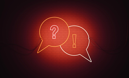 White and red neon speech bubble pair with question mark and exclamation point symbols sitting over black wall. Horizontal composition with copy space. Q and A and warning concept.
