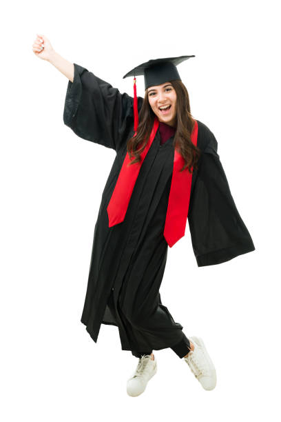 Full length of a caucasian young woman wearing a graduation gown. Pretty female graduate dancing and celebrating her academic success after getting a college degree