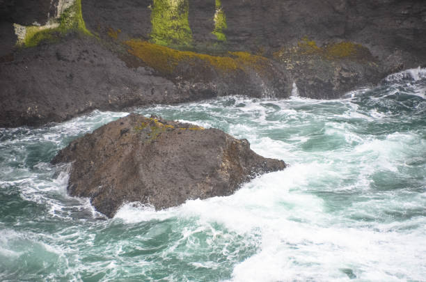istock Pacific ocean waves splashing against huge rocks and cliff 1301861401