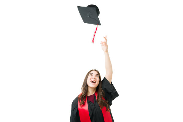 Excited young female graduate throwing her graduation cap in the air and celebrating after getting a university diploma