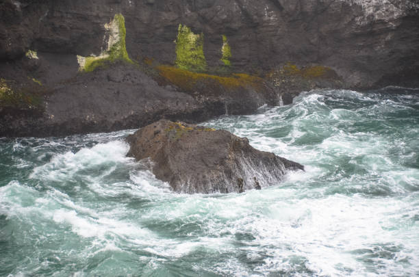 istock Pacific ocean waves splashing against huge rocks and cliff 1301861529