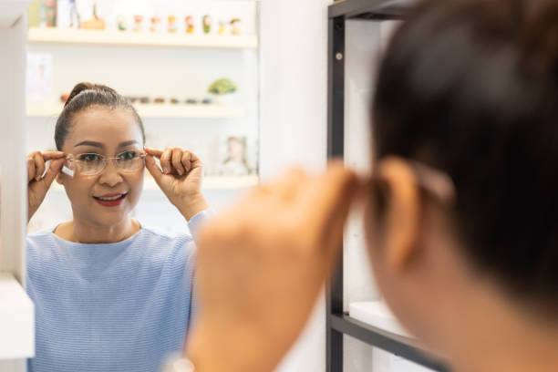 istock Selective focus at the mirror.  Senior elder Asian women smile and look at the mirror while choosing beautiful glasses frame trial inside of optical shop, store.  Eye sight for elder, healthcare. 1301868130