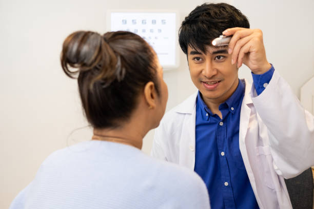istock Selective focus at Optometrist face. While doctor using penlight and subjective refraction to  examine eye visual system of elder patient women with professional machine before made glasses. 1301868365