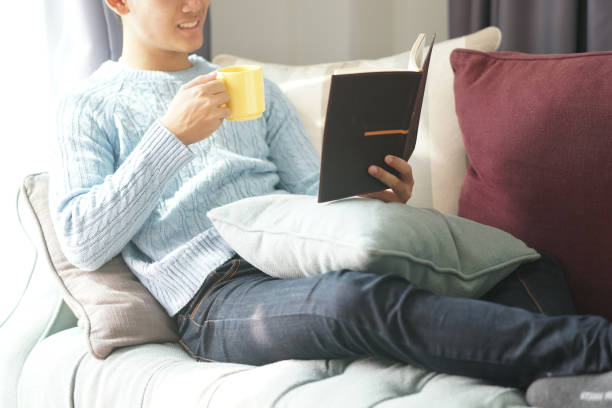 istock asian man reading book relaxing on sofa at home 1301871282