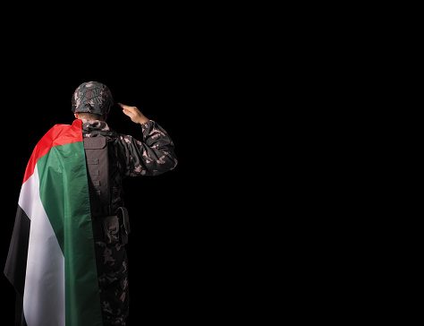 Solider and UAE flag. Concept - UAE national holidays, National Day, Commemoration Day.