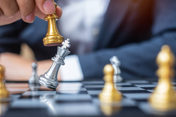 istock businessman hand moving gold Chess King figure and Checkmate opponent during chessboard competition. Strategy, Success, management, business planning, disruption and leadership concept 1301882620