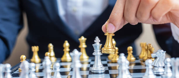 istock businessman hand moving gold Chess King figure and Checkmate opponent during chessboard competition. Strategy, Success, management, business planning, disruption and leadership concept 1301883146