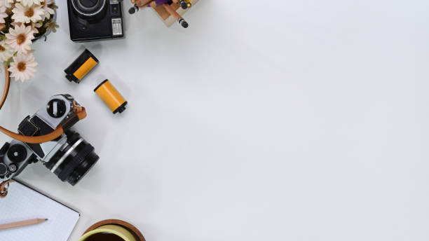 istock Top view of photographer workplace with camera, film, notebook and copy space on white table. 1301887320