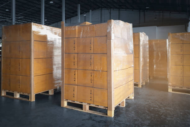istock Interior of storage warehouse with stack of card board boxes wrapped plastic on pallet rack. L-shape pallet corrugated paper cardboard Angle corner edge protector. shipping distribution warehouse. 1301889064