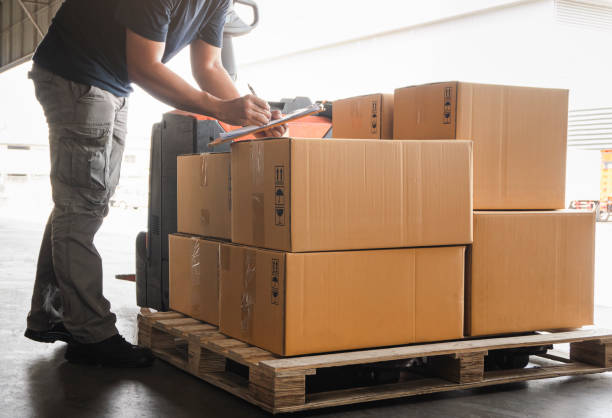 istock Warehouse worker holding clipboard his doing inventory management cargo boxes. Checking stock. Shipment boxes. Warehousing storage. 1301889073