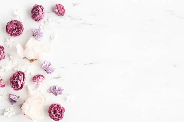 Photo of Flowers composition. White and purple flowers on marble background. Flat lay, top view