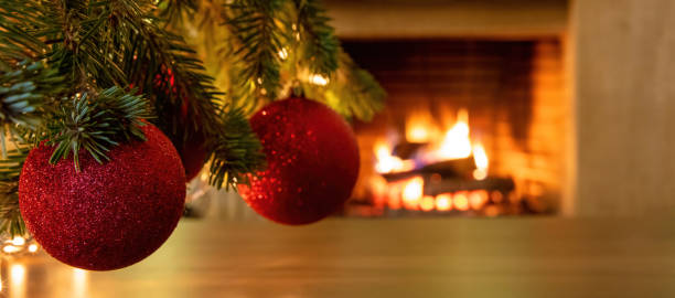istock Xmas red balls on tree branch, burning fireplace background 1301895560