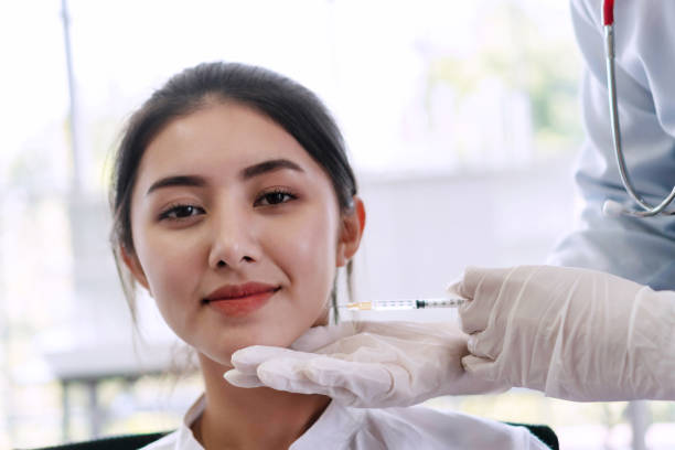 belle jeune femme asiatique recevant le traitement botulinum d’injection de toxine pour la qualité de l’ascenseur de visage. main du docteur retenant la seringue injectant la chirurgie botulique de toxine pour le traitement du visage de femmes de ride - bacille botulique photos et images de collection