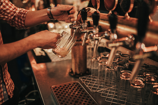 Holding a beer glass below the tap and pouring craft beer