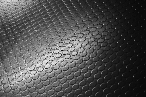 Shiny black dotted rubber carpet relief. Background photo with selective soft focus