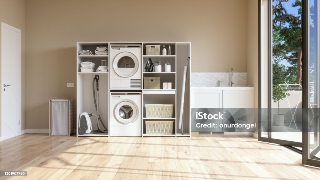 Laundry Room With Beige Wall And Parquet Floor With Washing Machine, Dryer, Laundry Basket And Folded Towels In The Cabinet. Utility Room Stock Photo