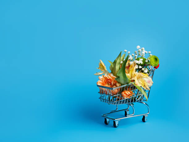 istock Flowers in small shopping trolley on blue background 1301908603