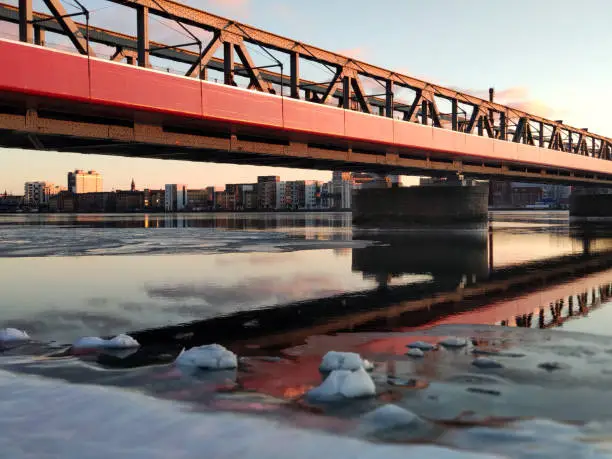 Photo of Red pedestrian bridge over frozen water at sunset in Denmark