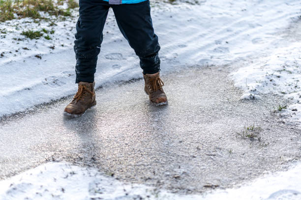 istock Child slides over a frozen puddle in winter 1301910719