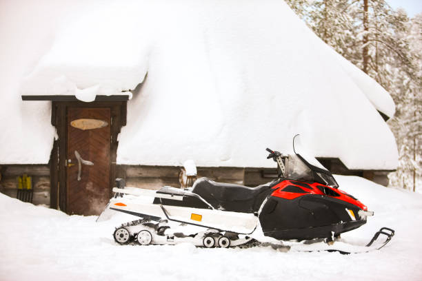 赤いスノーモービルは、赤いスノーモービルが冬の家の小屋の背景に雪の上に立っている冬の景色の背景に雪の上に立っています。 - snowmobiling snow winter mountain ストックフォトと画像