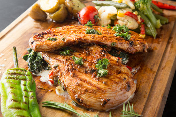 istock Grilled chicken breast with vegetables on a wooden cutting board 1301911832