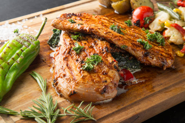 istock Grilled chicken breast with vegetables on a wooden cutting board 1301911837