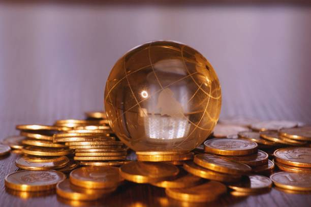 istock A small glass globe with coins on a colored background. 1301912514