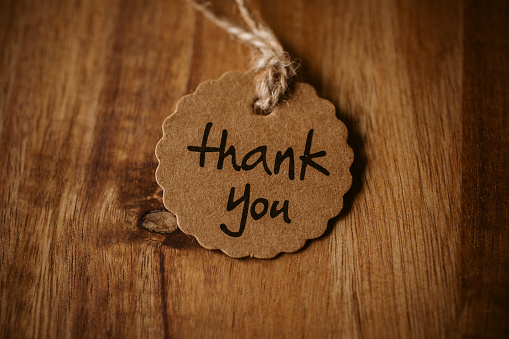 Thank you word written in a card on wooden background with selective focus. Love and gratitude concept.