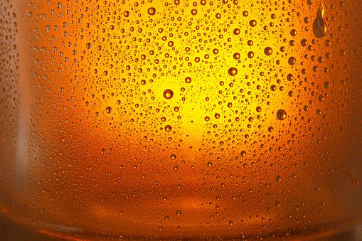 Condensation on  Drinking glass - glass bottle. Ice Cold Beer glass With Water Drops  Orange backgrounds