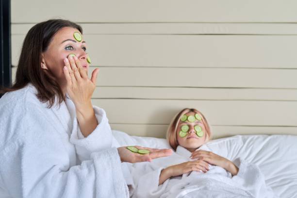 Mom and teenage daughter taking care of face using natural cosmetics and cucumber Relaxation together, beauty treatments. Mom and teenage daughter are taking care of face using natural cosmetics and cucumber masks. Beauty, clean spa skin care, parent teen child communication women facial mask mud cucumber stock pictures, royalty-free photos & images