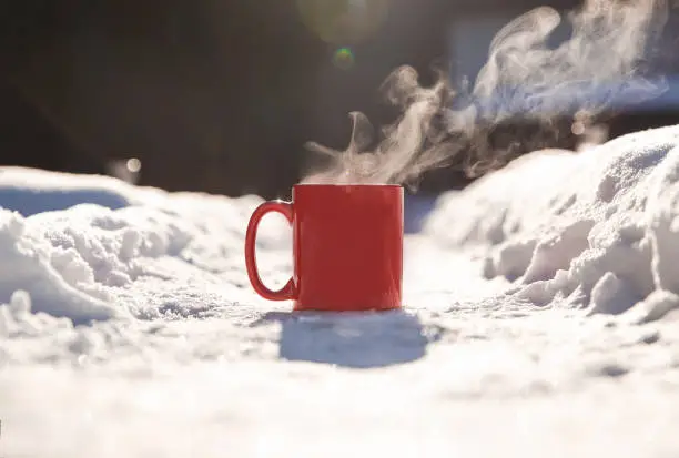 Steaming cup of hot coffee,tea or chocolatemilk in the cold fresh white snow, Winter,cozy,drink,snowy day concept background in nature beauty