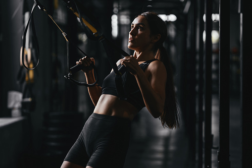 Fit young woman at a gym style on dark gray background. Fitness, functional, training, and lifestyle concept
