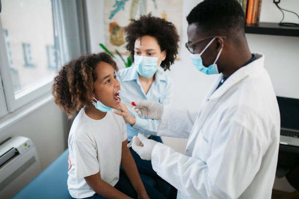 High angle view of a little African American girl doing a swab test High angle view of a young African American girl taken into a medical clinic by her mother to get tested for a corona virus, taking a mouth swab test medical swab stock pictures, royalty-free photos & images