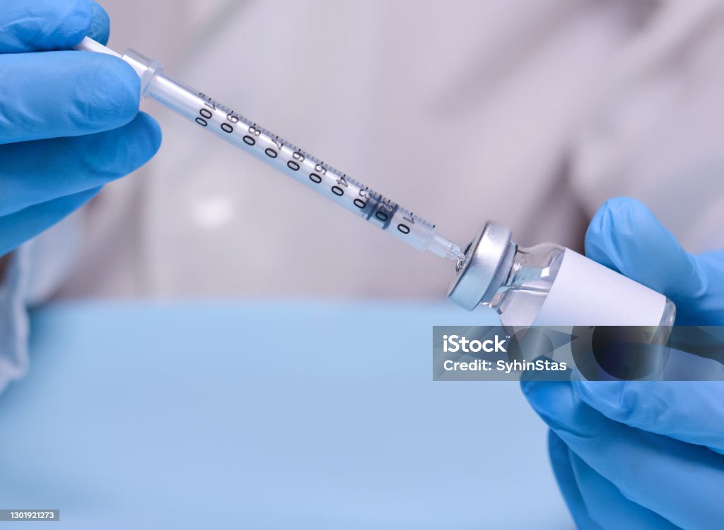 Doctor in protective medical gloves holds a vial with a vaccine and a syringe.The concept of medicine, healthcare and science.Coronavirus vaccine.Copy space for text. Alternative Therapy Stock Photo