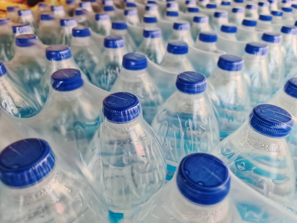 große anzahl von verpackten abgefüllten trinkwasser mit blauen kappen - wasserflasche stock-fotos und bilder