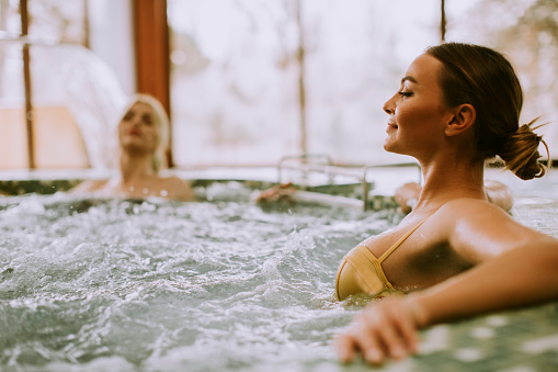 Pretty young women relaxing in the whirlpool bathtub at the poolside