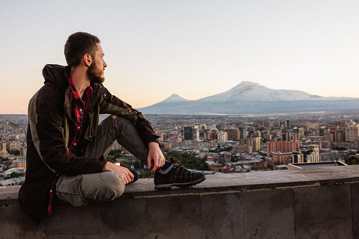 Young man at the Yerevan city and Mount Ararat background at the sunset in Armenia