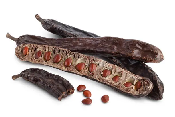 Photo of Ripe carob pods and bean isolated on white background with clipping path and full depth of field
