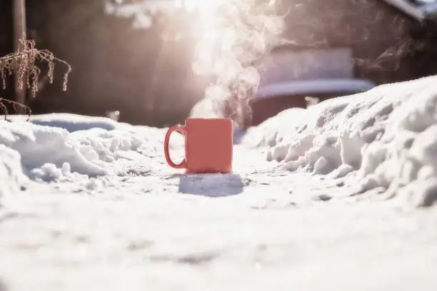 Steaming cup of hot coffee,tea or chocolatemilk in the cold fresh white snow, Winter,cozy,drink,snowy day concept background in nature beauty