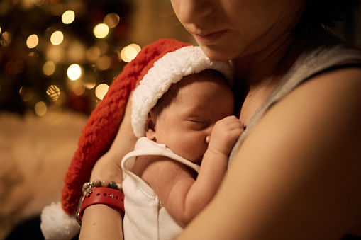 Happy young mother posing with newborn son under Christmas tree. High quality photo