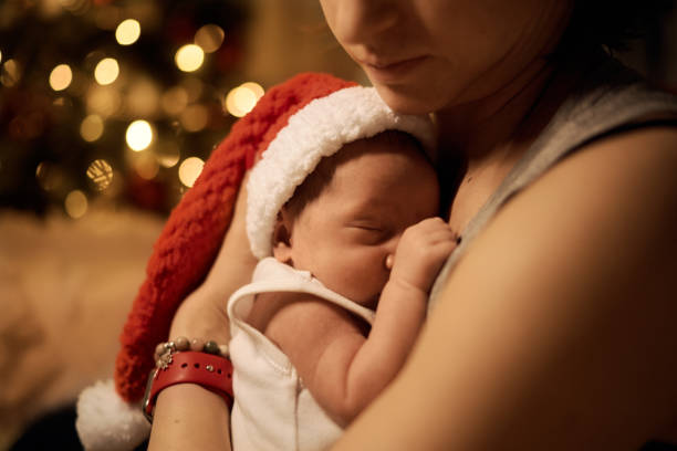 Happy young mother posing with newborn son under Christmas tree stock photo